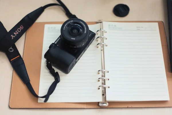 vintage camera with a notebook and a pen on a wooden background