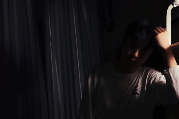 young man with a black hair in a dark room