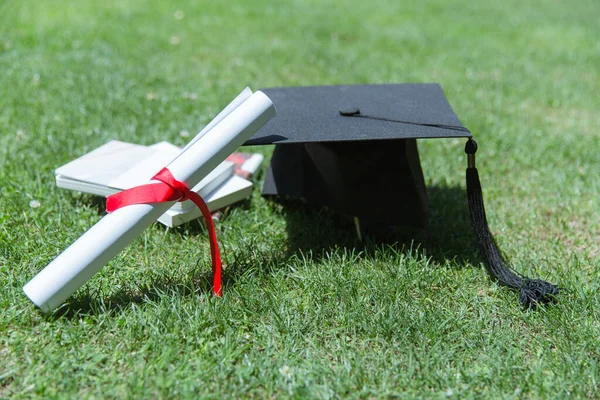 graduation cap and diploma on green grass