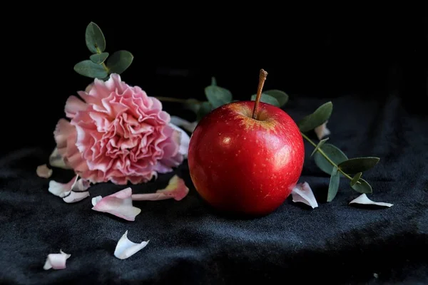 red apple and a black rose on a dark background
