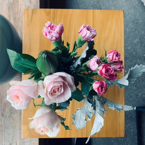 beautiful bouquet of roses in a vase on a wooden background