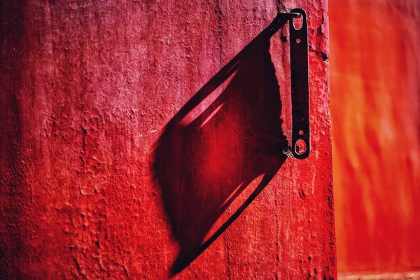 red and white wall with a metal handle
