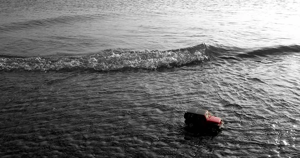 black and white photo of a man in a boat with a backpack on the sea