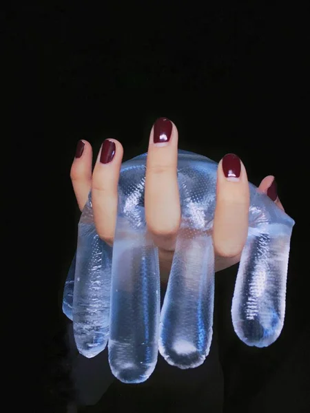 female hand with a pair of white socks on a black background