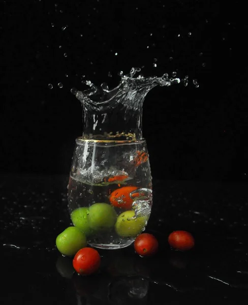 fresh water splash with drops of fruits on black background
