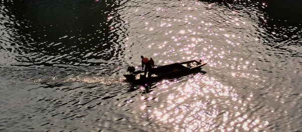 the silhouette of a man in a boat