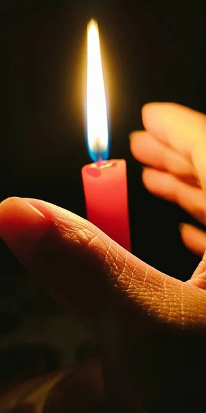 close up of a burning candle in a hand