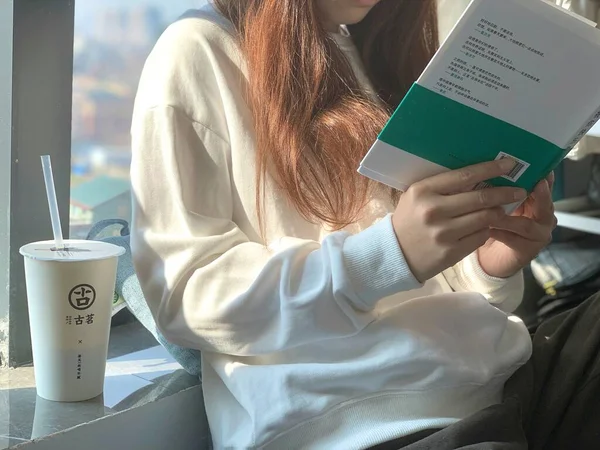 young woman reading book in cafe