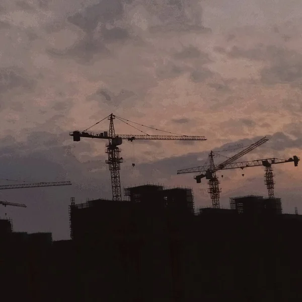 silhouette of a building with a crane and a house