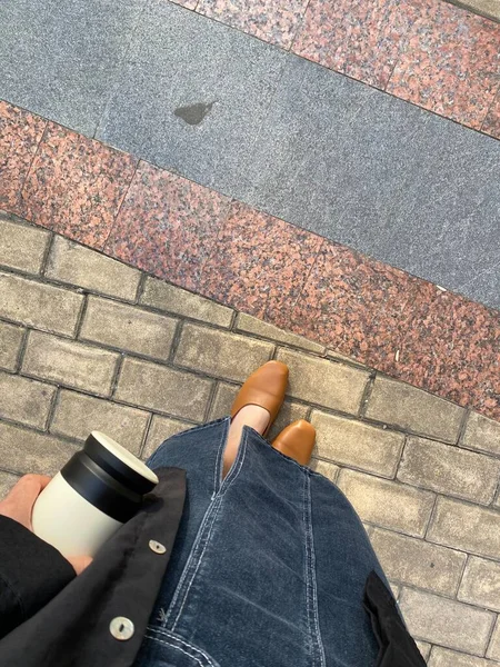 woman with cup of coffee and shoes on the street
