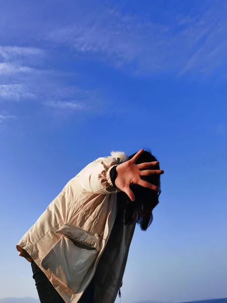 young man in a blue shirt and a white scarf on a background of a cloudy sky