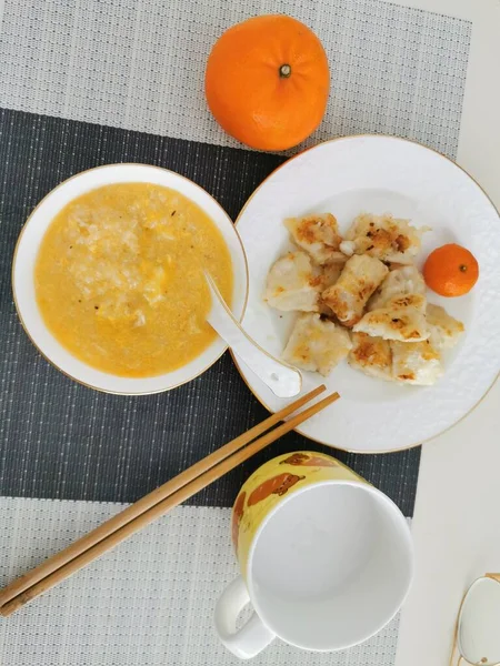 a bowl of delicious pumpkin soup with a cup of tea on a white plate