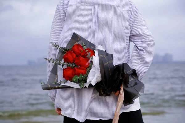 a man with a bouquet of flowers and a gift