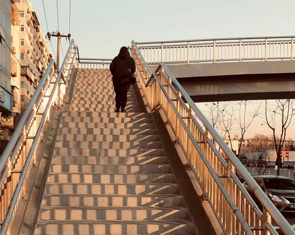 a man is walking on the stairs of the bridge.