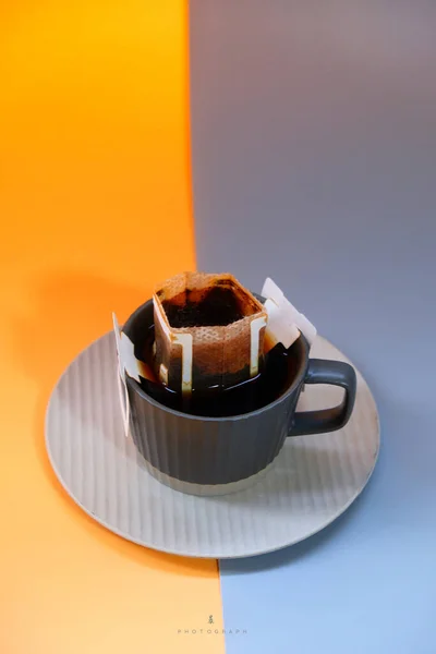 a cup of coffee with a piece of lemon on a blue background