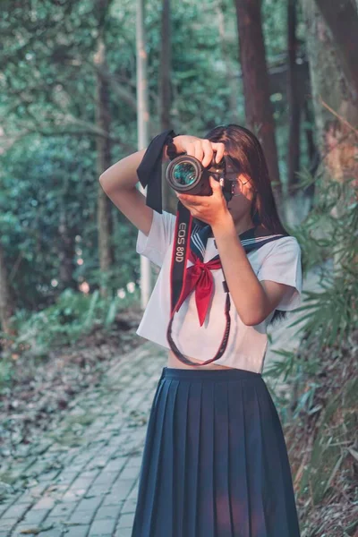 young beautiful girl with a camera in the forest