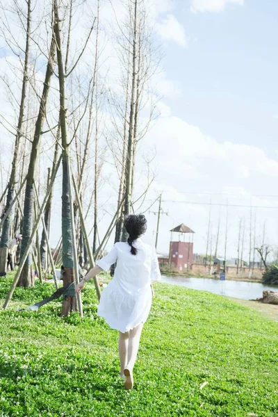 young woman in white dress and hat walking in park
