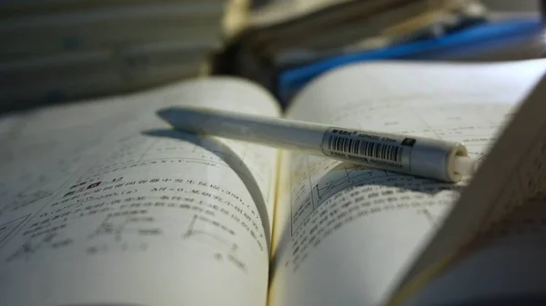 close up of a book with a pen and a pencil