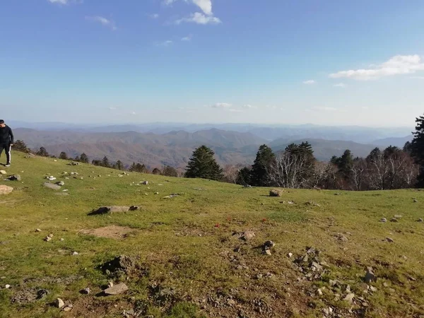 a man in a green jacket is hiking in the mountains