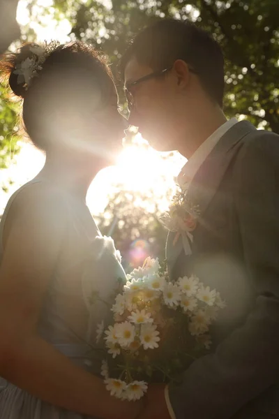 bride and groom kissing on the background of the sun