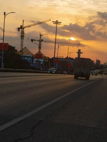 construction site with cranes and traffic at sunset