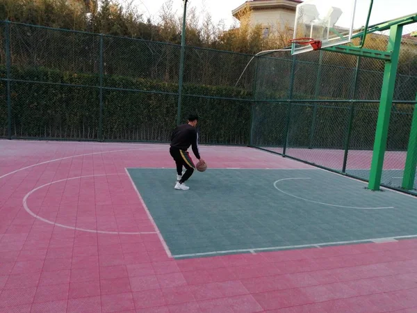 young man in a red t-shirt and a white sweatshirt on a tennis court