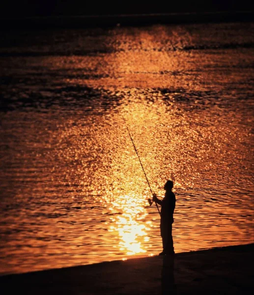 silhouette of a man fishing on the beach