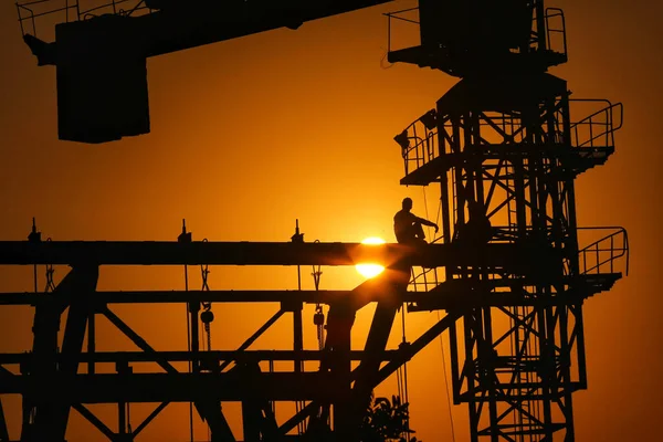 silhouette of a industrial factory cranes on the background of the setting sun