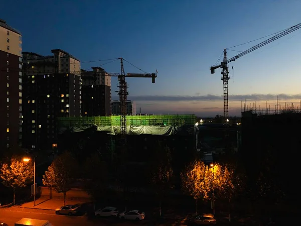 construction cranes and building under the sunset sky