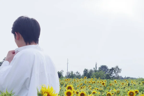 young man in a white shirt and a hat with a sunflower in his hand