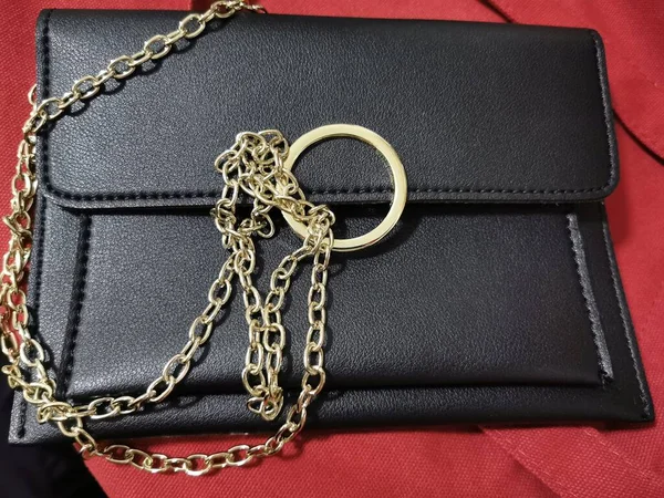 black leather bag with a chain on a red background
