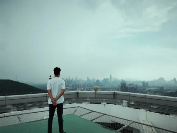 man in black suit and white shirt standing on the roof of the city