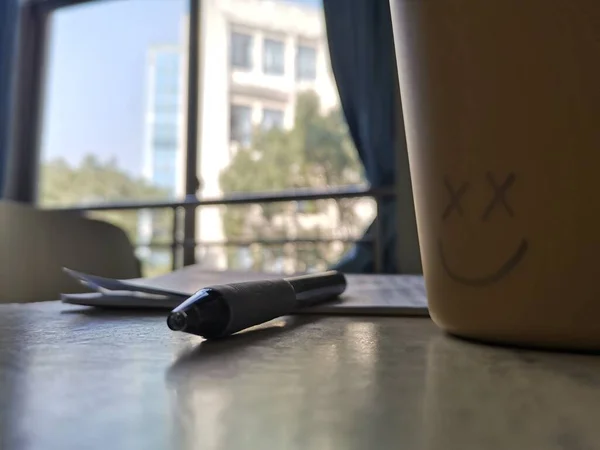 close up of a glass of coffee and a pen