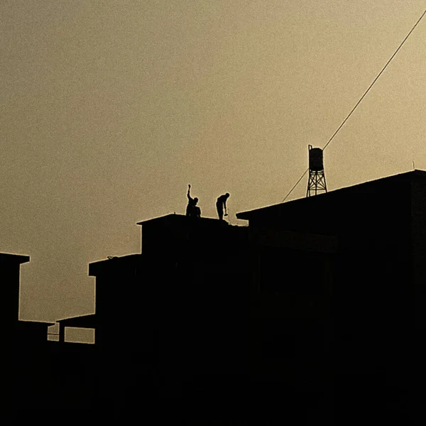 silhouette of a man and woman on the roof of the building