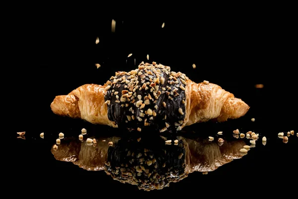 croissant with sesame seeds on black background