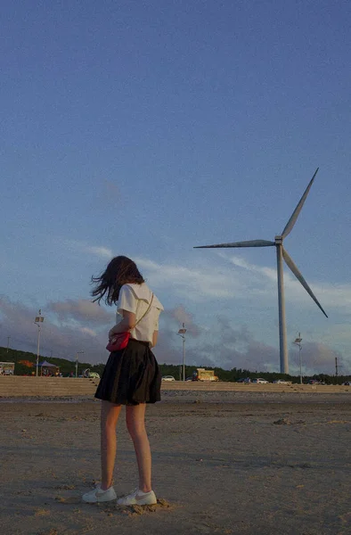 young woman with wind turbine on the beach
