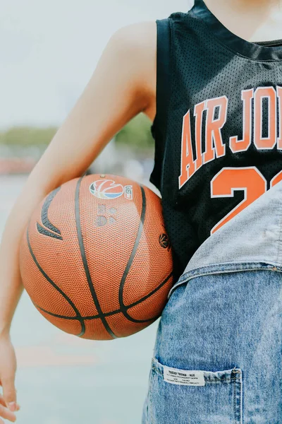 young woman with basketball ball on the beach