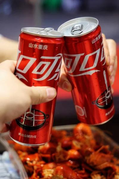 hand holding a glass of cola with a red hot drink