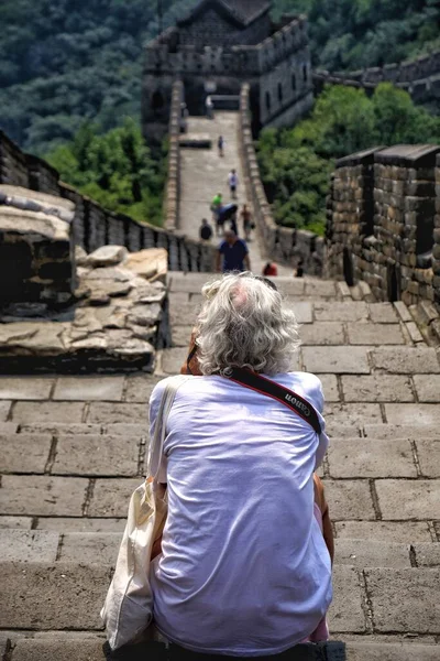 old woman in a hat with a backpack on the background of the ancient castle