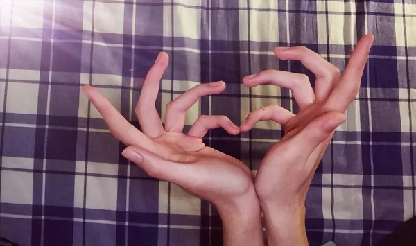 hands of a woman in a white shirt and a heart shape with a hand on a wooden background