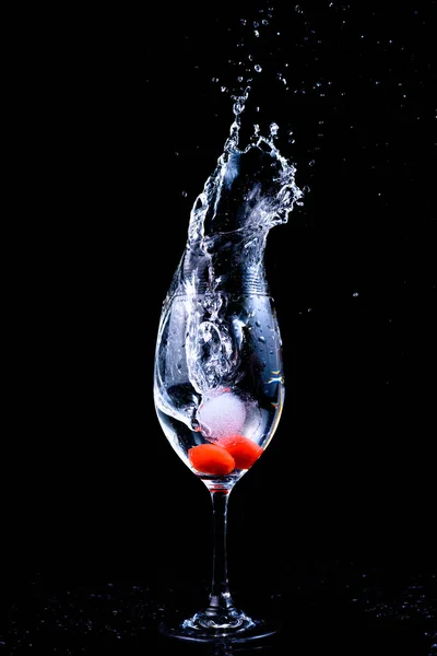 red wine splashing into glass on black background