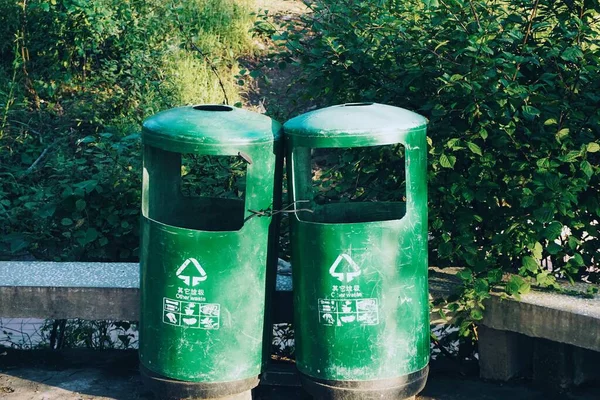 green trash can with recycle bin in the park