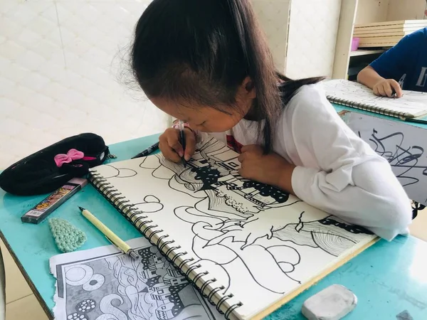 little girl draws a pencil on the floor