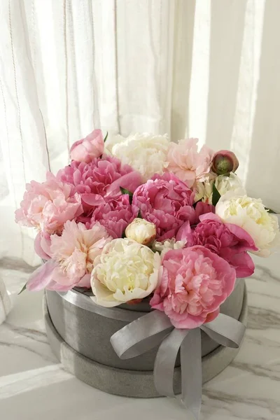 beautiful bouquet of peonies in a white vase on a light background.