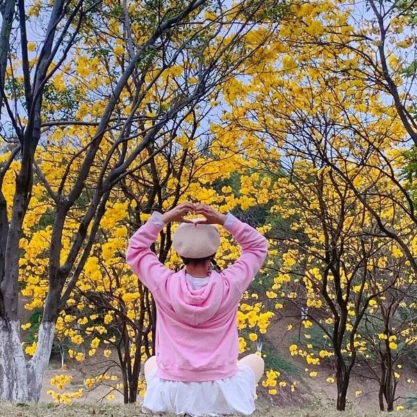 young woman in a yellow jacket and a hat with a scarf in the park