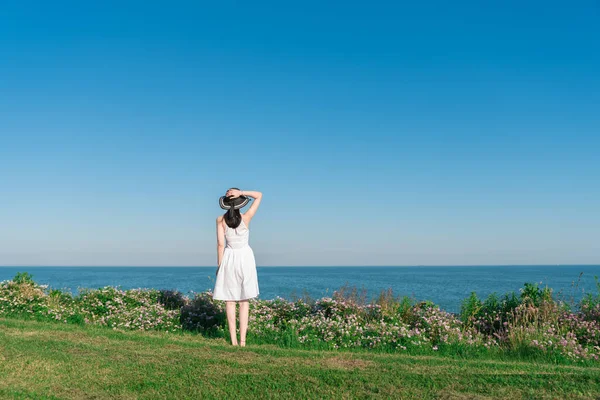 young woman in a white dress and hat on the beach