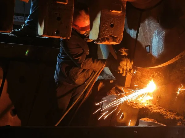 industrial worker welding metal with sparks and grinder