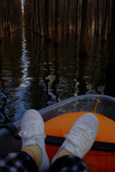 man in a hat and boots sitting on the floor and looking at the water.
