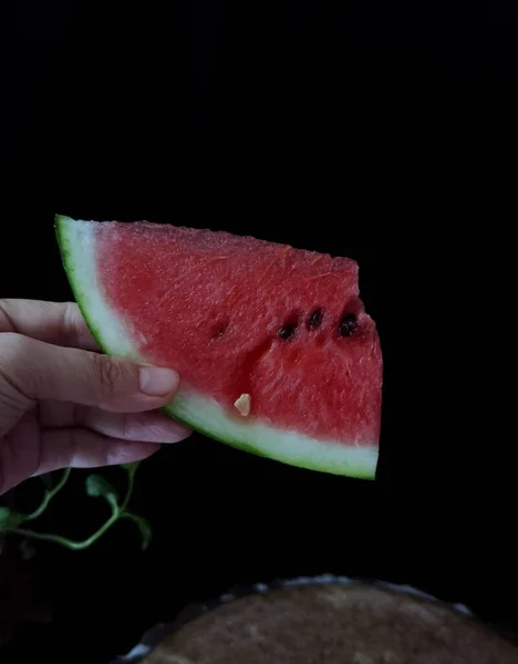 slice of red watermelon on a black background