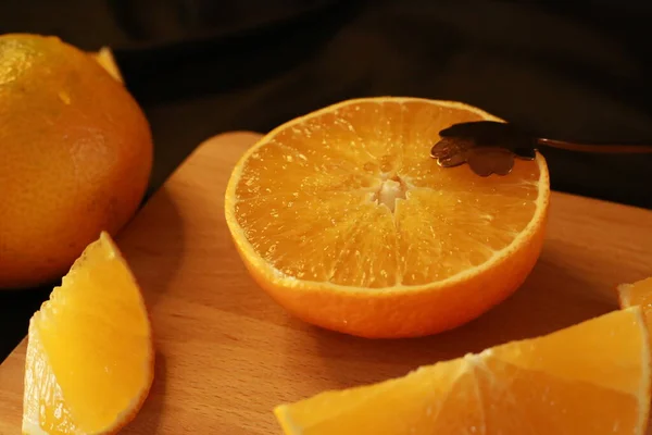 fresh orange and sliced oranges on wooden table